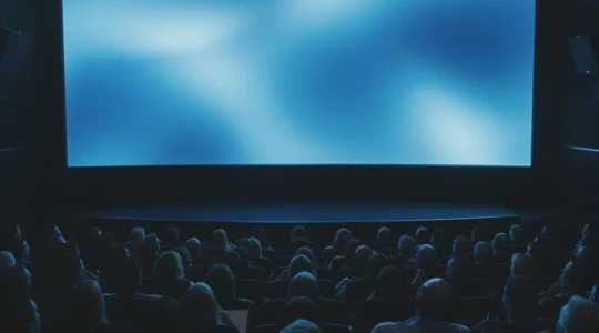 Salle de cinéma remplie de spectateurs captivés regardant un grand écran dans la pénombre, ambiance bleue électrique