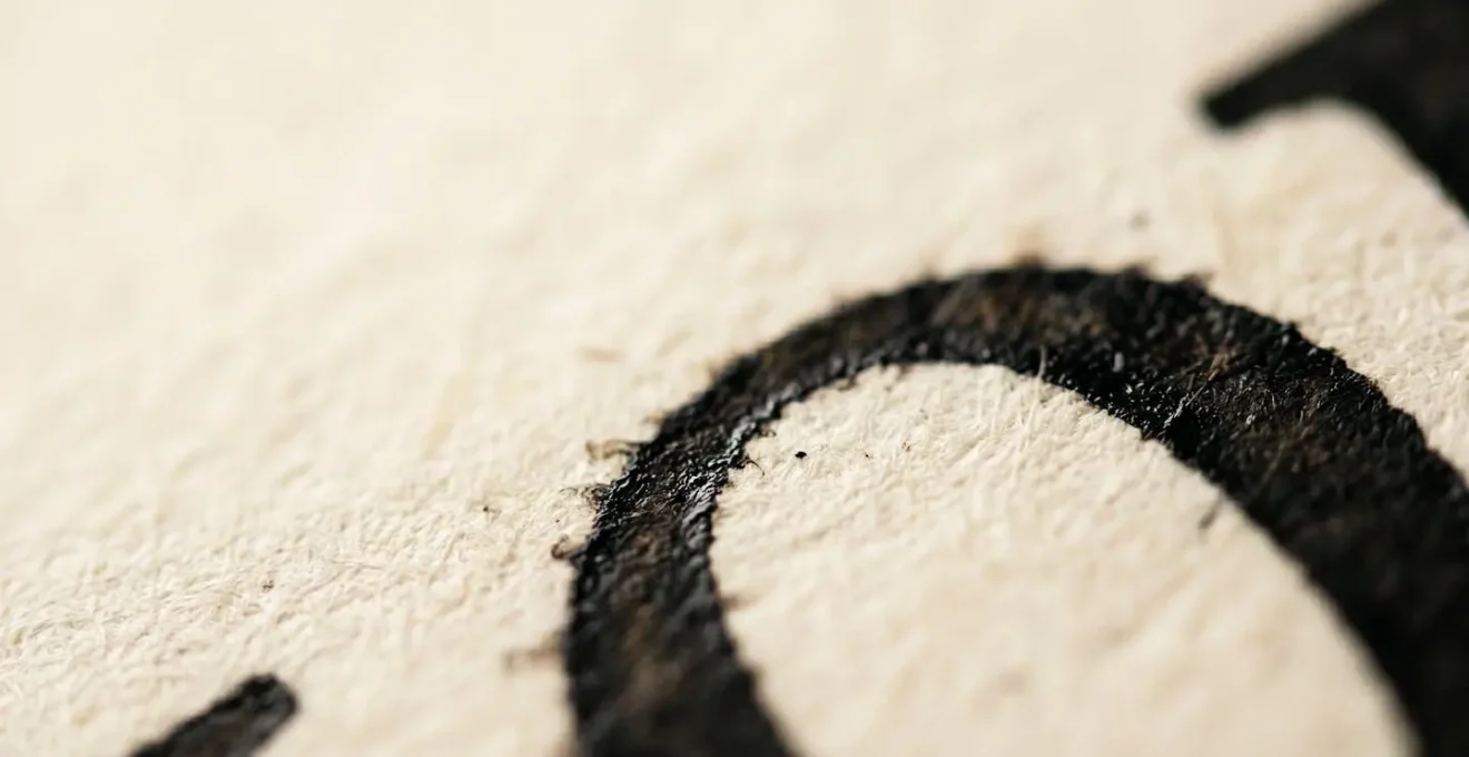 Vue macro de caractères typographiques montrant la texture et le contraste entre l'encre et le support, avec profondeur de champ réduite