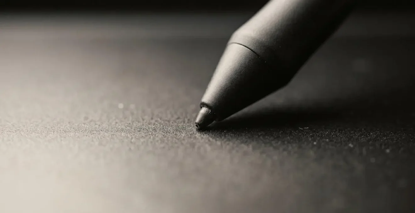 Gros plan extrême de la pointe d'un stylet numérique en contact avec la surface d'une tablette graphique